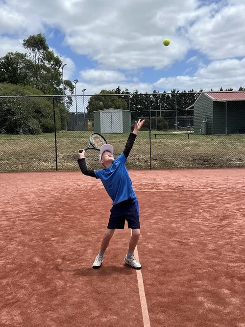 Junior player practising a tennis serve